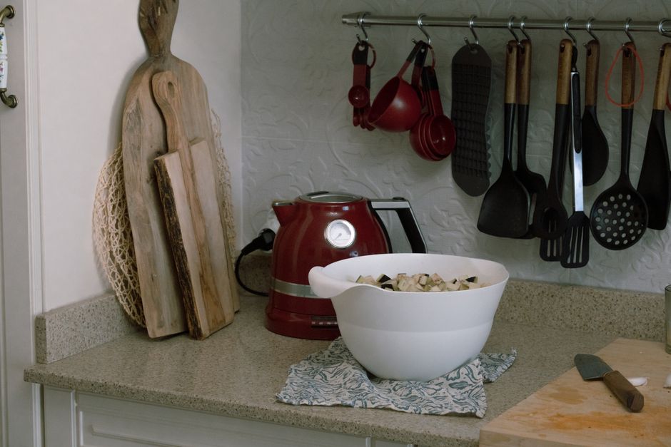 A cozy kitchen countertop with utensils, a kettle, and a bowl of fresh ingredients.